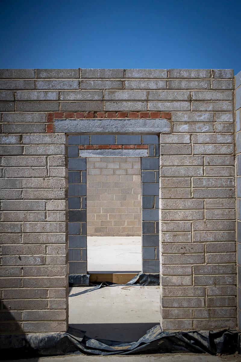 Structural blockwork and facing brickwork are rising rapidly, transitioning this high-end residential build from a ground-level footprint into a highly defined, physical space. The perimeter and internal partition walls are quickly taking shape, establishing the core layout and rooms of the property.