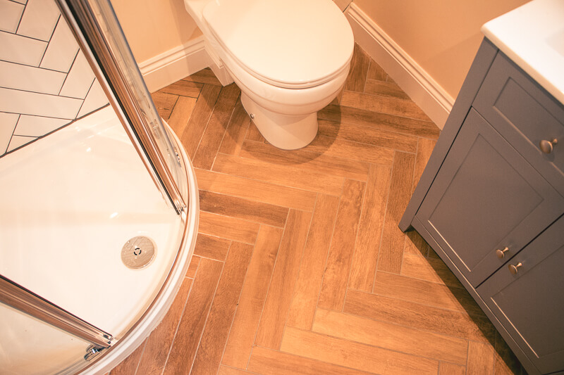 Shower room fitted with wood effect tiles and corner shower to maximise use of space.