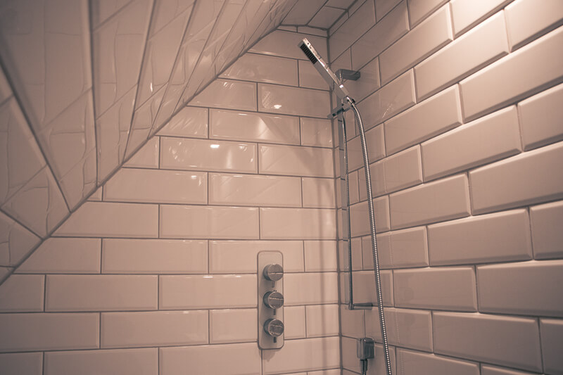 Elegant tiling making use of under the eaves space to create additional shower.